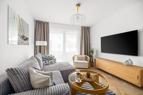 a living room with a couch and a tv at Rezydencja Merwede Aparthotel - My Rest in Gdańsk