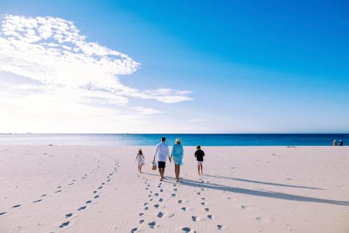 a group of three people walking on the beach at Smiths Beach Resort in Yallingup