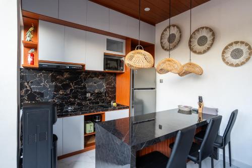a kitchen with white cabinets and a black counter top at 3BR Brand New Cozy Private Villa D'Pondok Balangan in Uluwatu