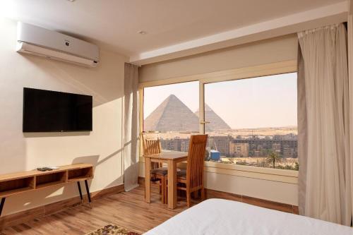 a hotel room with a desk and a view of the pyramids at Golden pyramids group in Nazlet el-Sîsi