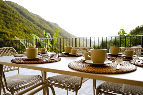 a table with cups and saucers on a balcony at Old Village Linda - Tra Lunigiana & Cinque Terre in Comano