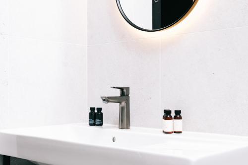 a bathroom sink with a mirror and two bottles on it at Getaway Studios Liège in Liège