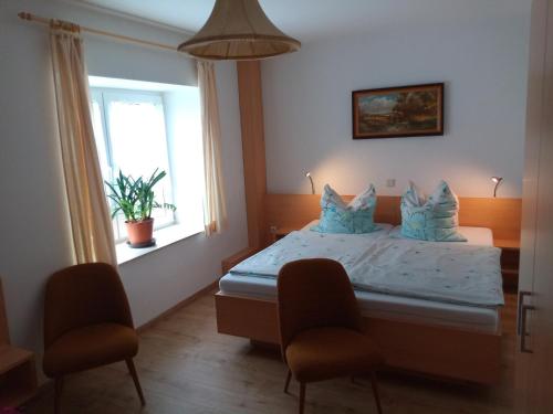 a bedroom with a bed with two chairs and a window at Ferienwohnung Kuhstall in Reinhardtsdorf