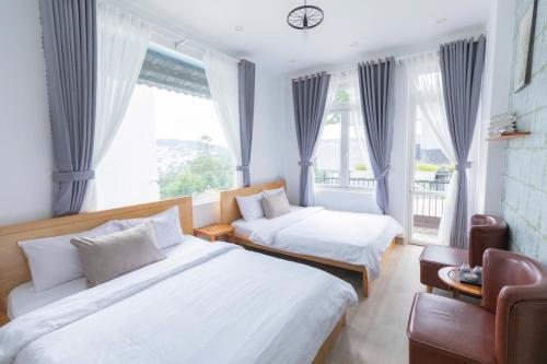a hotel room with two beds and a window at Blue Windy Đà Lạt Homestay in Da Lat