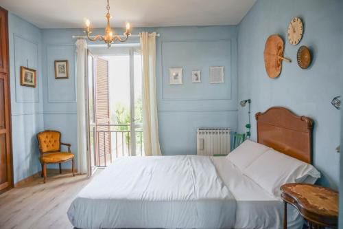 a bedroom with a bed and a chair and a chandelier at Il Biru in Montelupo Albese