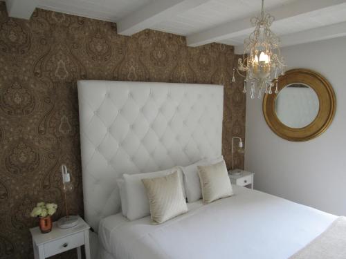 a bedroom with a white bed and a mirror at Orewa Beachcomber in Orewa