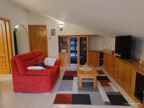 a living room with a red couch and a table at Casa vacanze DAL CASTELIN in Sondrio