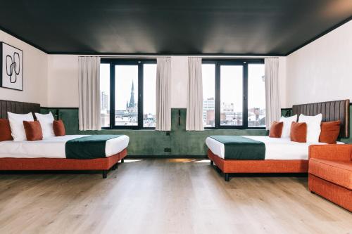 two beds in a room with large windows at Getaway Studios Liège in Liège