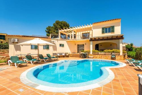a villa with a swimming pool in front of a house at Villa Caballero by Villa Plus in Punta Prima