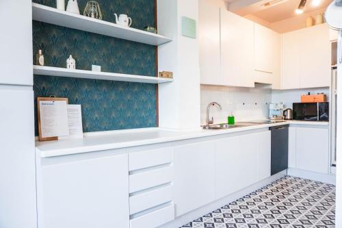 a kitchen with white cabinets and a tile floor at Il Biru in Montelupo Albese