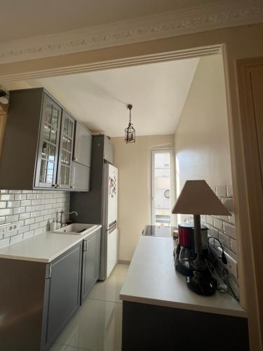 una cucina con mobili bianchi e una lampada su un bancone di Cosy Appartement a Boulogne-Billancourt