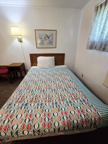 a bed in a room with a colorful quilt on it at OYO Sandman Inn in Eagle Grove