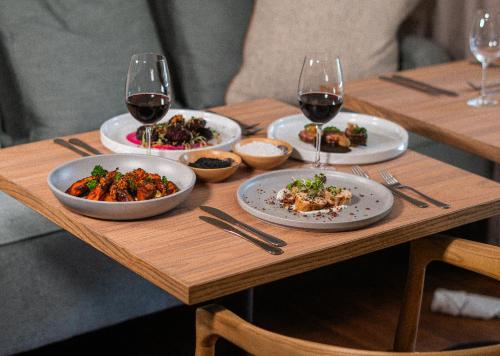 a wooden table with plates of food and glasses of wine at 10 2nd Avenue Houghton Estate by Dream Resorts in Johannesburg