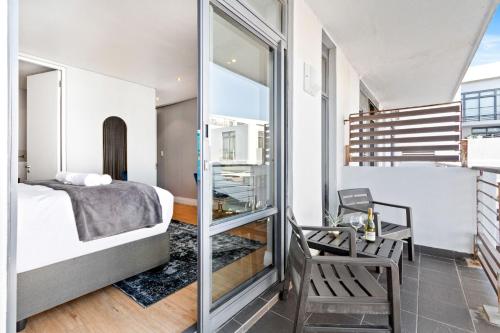 a bedroom with a bed and a glass door leading to a balcony at Eden on the Bay 190 by Host Agents in Cape Town