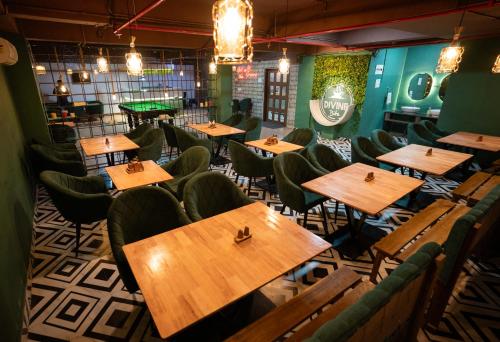 a restaurant with wooden tables and green chairs at Hotel Shubham Grand in Bhubaneshwar