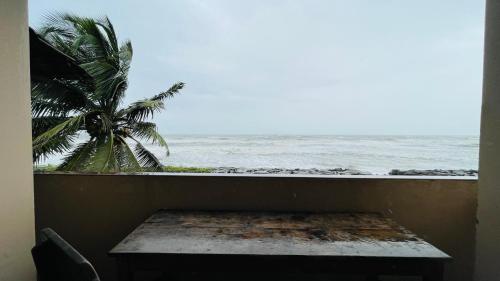 a window with a view of the ocean and a palm tree at Beach at Deltin in Udupi