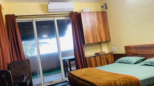 a bedroom with a bed and a large window at Beach at Deltin in Udupi