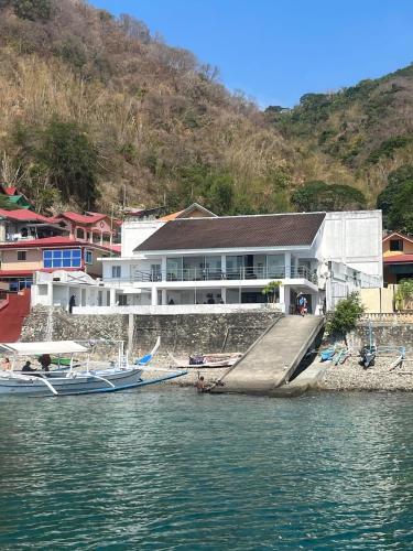 a building on the shore of a body of water at Villa Ebarle Diving Resort in Mabini