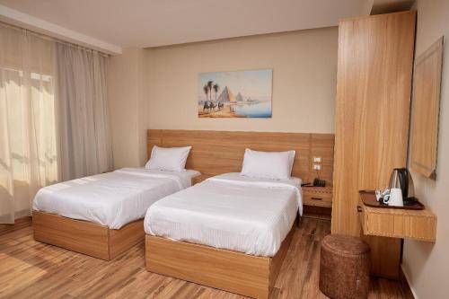 a hotel room with two beds and a television at Golden pyramids group in Nazlet el-Sîsi