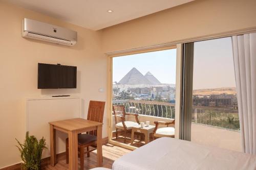 a room with a bed and a view of the pyramids at Golden pyramids group in Nazlet el-Sîsi