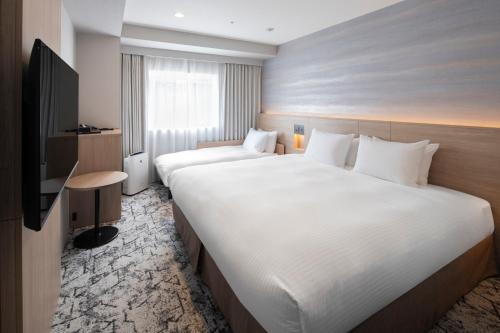 a hotel room with two beds and a television at La'gent Stay Sapporo Odori Hokkaido in Sapporo