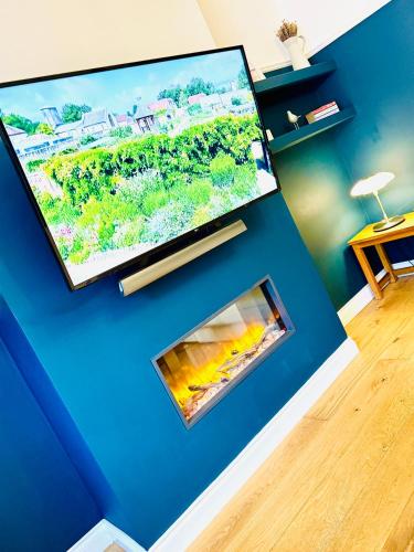 a living room with a tv and a fireplace at HomeDecor Cottages - Castle Walk House in Alnwick