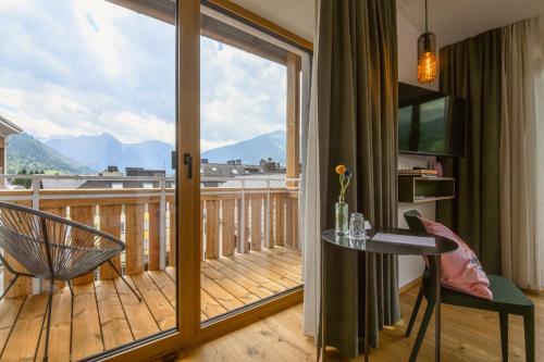 a room with a balcony with a table and a window at Hotel Blü Gastein in Bad Hofgastein