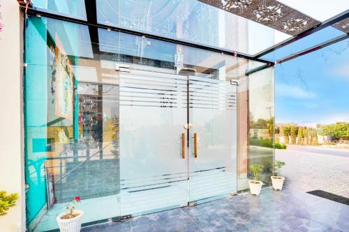 a pivot door in a glass building with plants at Hotel O Surya Enclave Aroma Regency in Meerut