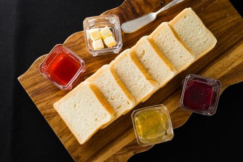 a wooden cutting board with bread and different types of condiments at La'gent Stay Sapporo Odori Hokkaido in Sapporo