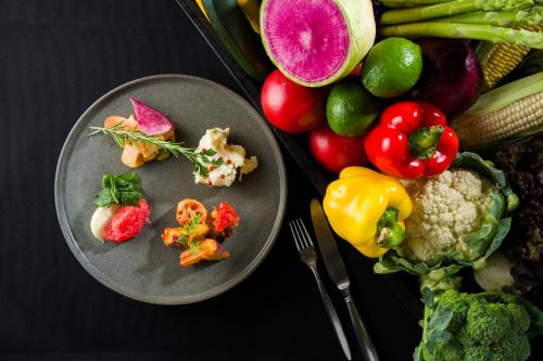 two plates of food on a table with fruits and vegetables at La'gent Stay Sapporo Odori Hokkaido in Sapporo