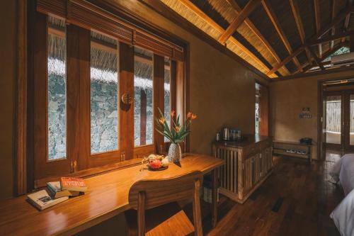 a room with a table with a vase of flowers on it at Tam Coc Golden Fields Retreat in Vũ Lâm