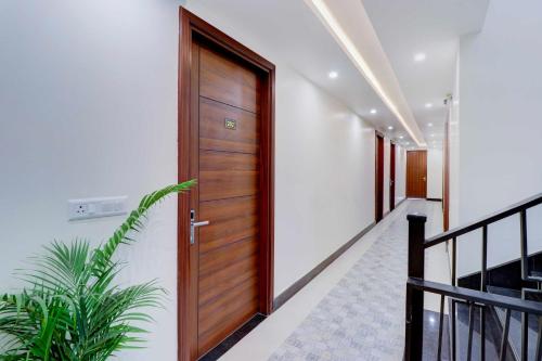 a wooden door in a hallway with a plant at Collection O FRI Dehradun Hotel EL Portrait in Dehradun