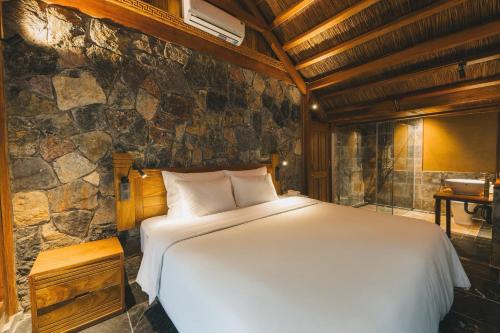 a bedroom with a large bed in a stone wall at Tam Coc Golden Fields Retreat in Vũ Lâm