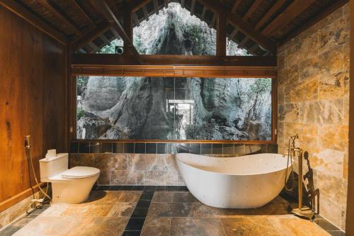 a bathroom with a tub and a toilet at Tam Coc Golden Fields Retreat in Vũ Lâm