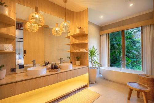 een badkamer met 2 wastafels en een bad bij Suara Air Luxury Villa Ubud in Ubud