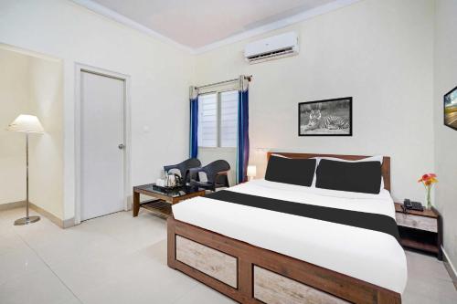 a bedroom with a bed and a desk and chairs at Collection O Hebbal Mysore in Mysore