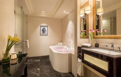 a bathroom with a tub and a sink and a mirror at The Pury Hotel in Yiwu