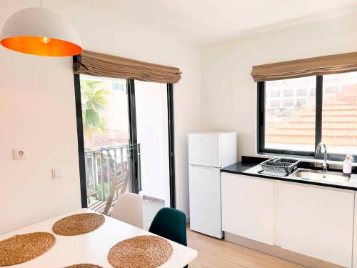 a kitchen with white cabinets and a table with a sink at BIA D'Olaf Apartments in Santa Maria