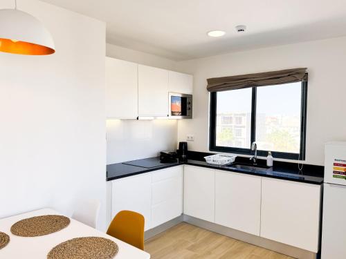 a kitchen with white cabinets and a table at BIA D'Olaf Apartments in Santa Maria