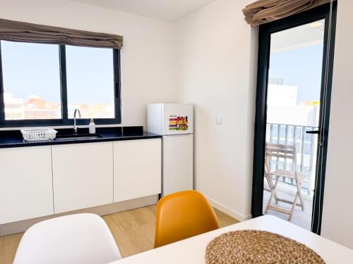 a kitchen with white cabinets and a sink and two windows at BIA D'Olaf Apartments in Santa Maria