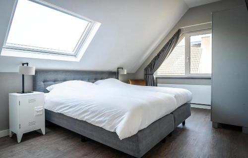 a bedroom with a large bed and two windows at B-10 Hodshonstraat in De Cocksdorp
