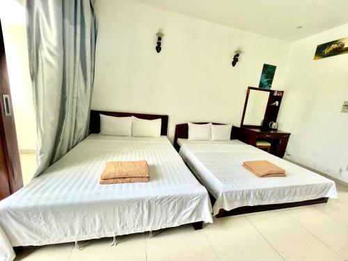 a bedroom with two beds and a mirror at Resort HAVANA in Mui Ne