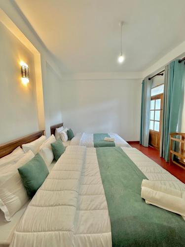 a large white bed in a room with a window at Highest Village Bungalow in Nuwara Eliya