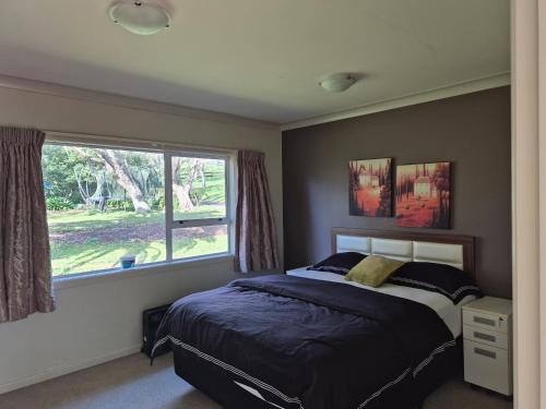 a bedroom with a bed and a window at Cozy FarmStay with Spa in Pokeno