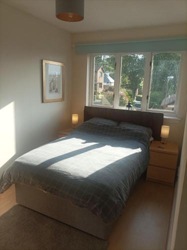 a bedroom with a bed and two windows at Double room, Belhaven, Dunbar in Dunbar