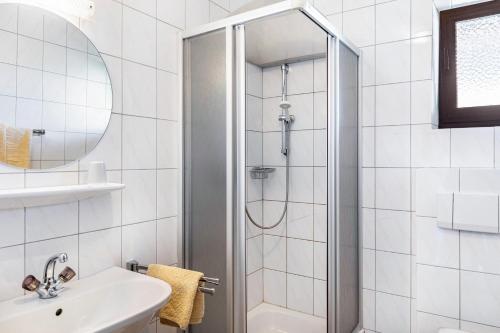 a white bathroom with a shower and a sink at Pension Heidelberg in Hopfgarten im Brixental