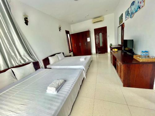 a hotel room with two beds and a television at Resort HAVANA in Mui Ne