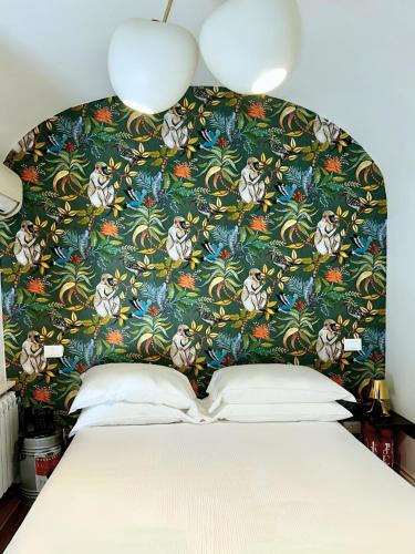 a bedroom with a large bed with a floral headboard at Ginevra Boutique Rooms - Palazzo Leosini - Residenze D'Epoca in LʼAquila