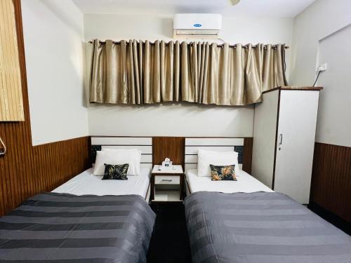 two beds in a small room with a window at Karachi Inn in Karachi