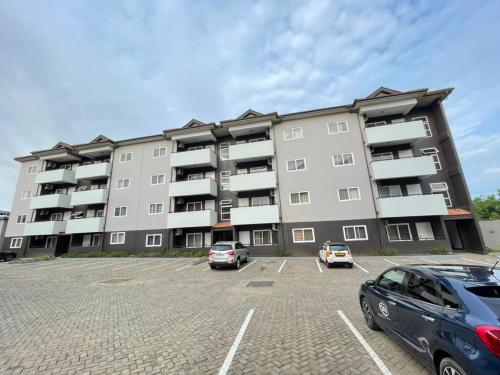 a large apartment building with cars parked in a parking lot at Sunny's Place Luxury Apartments in Accra